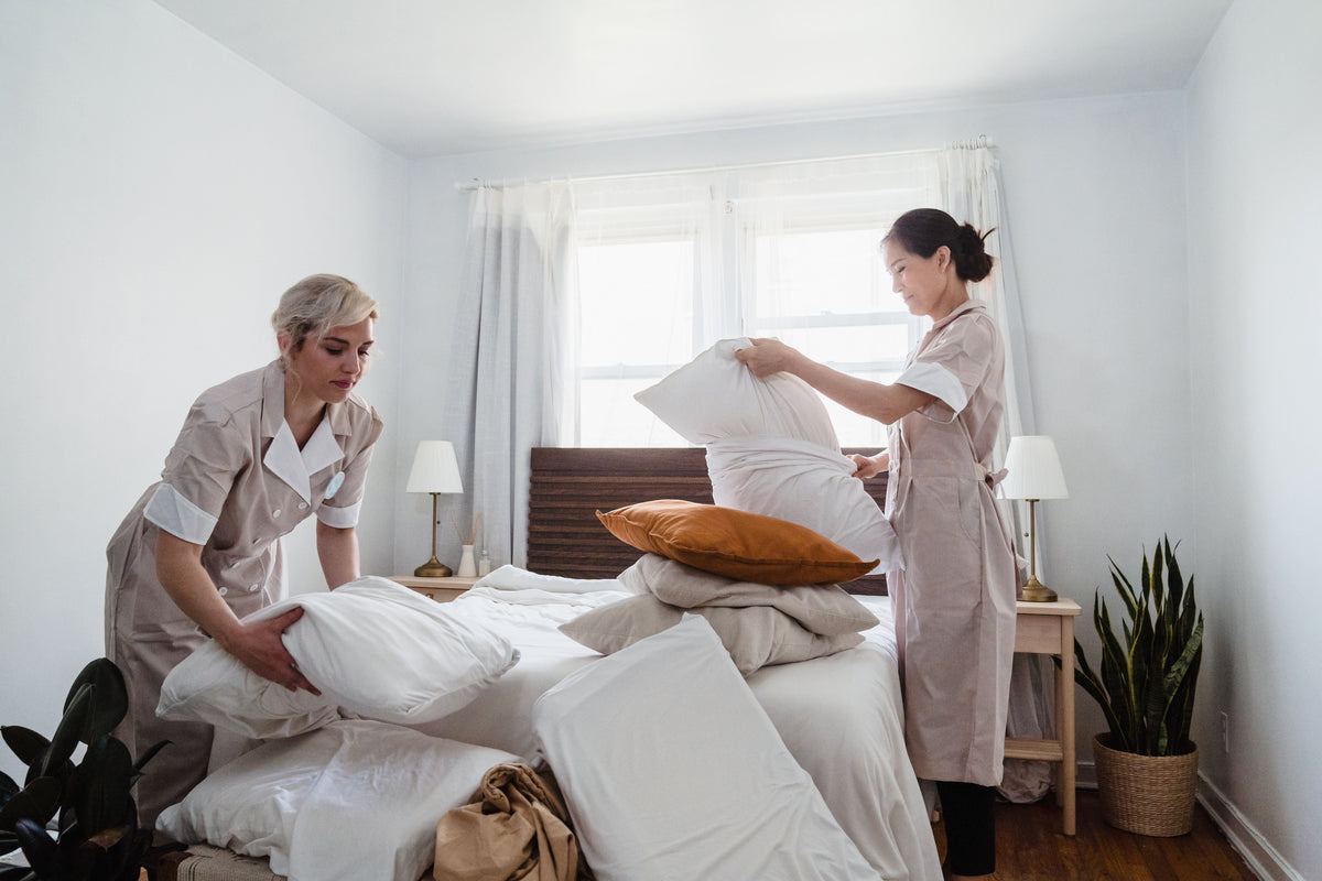 Two housekeepers changing the bedding in a hotel room between guests