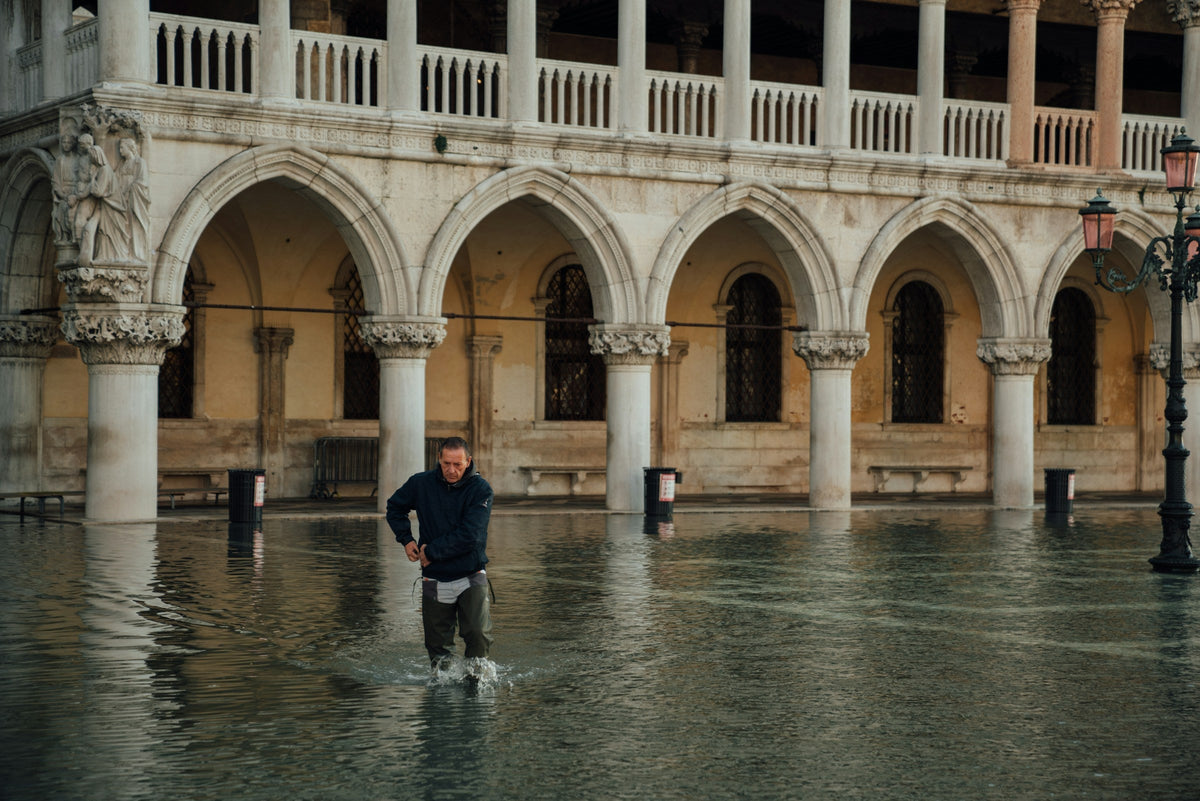 A man wades through high water in front of the arcades of the Doge's Palace in Venice during acqua alta