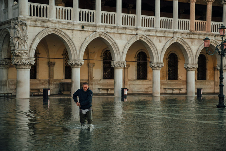 A man wades through high water in front of the arcades of the Doge's Palace in Venice during acqua alta