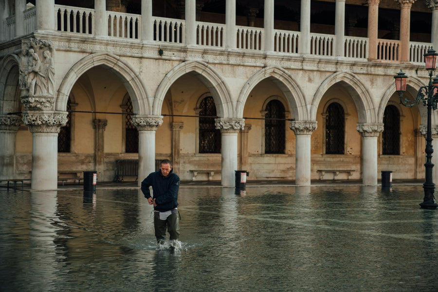 A man wades through high water in front of the arcades of the Doge's Palace in Venice during acqua alta