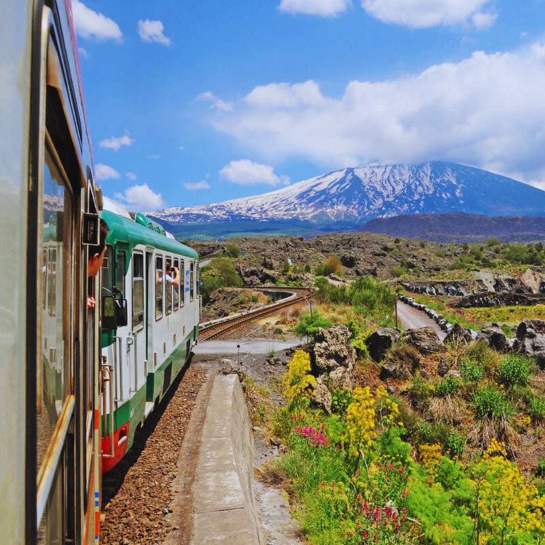 Circumetnea railcar crossing the lava fields below snowy Etna