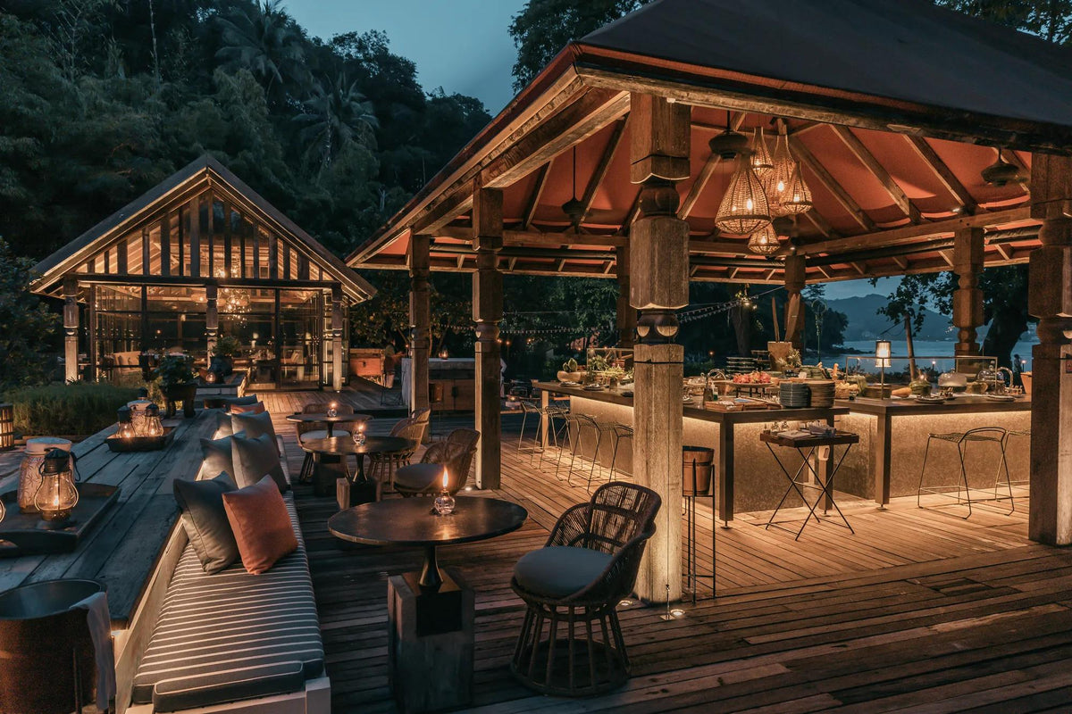 Open-air Thai pavilions lit at dusk at Ta Khai, Rosewood Phuket