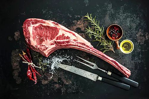 Tomahawk steak with herbs and spices before grilling at Carnivore Steak & Grill