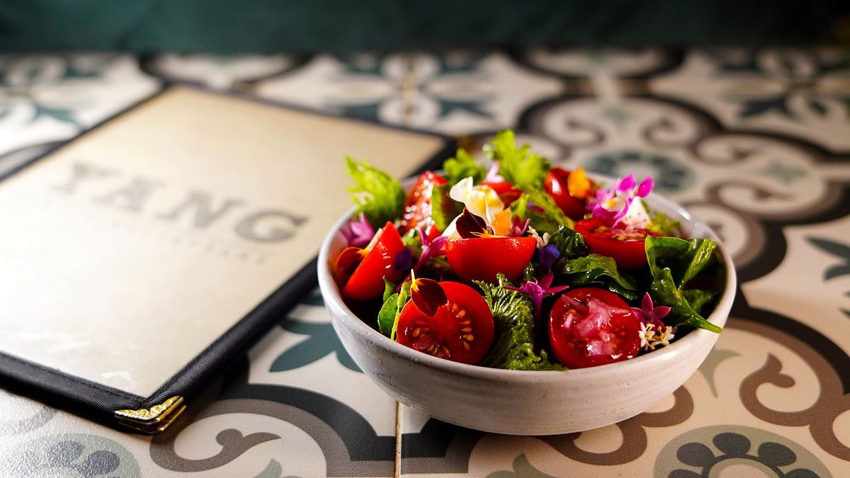 A fresh salad bowl beside the menu at Yang Garden Restaurant, Saladan