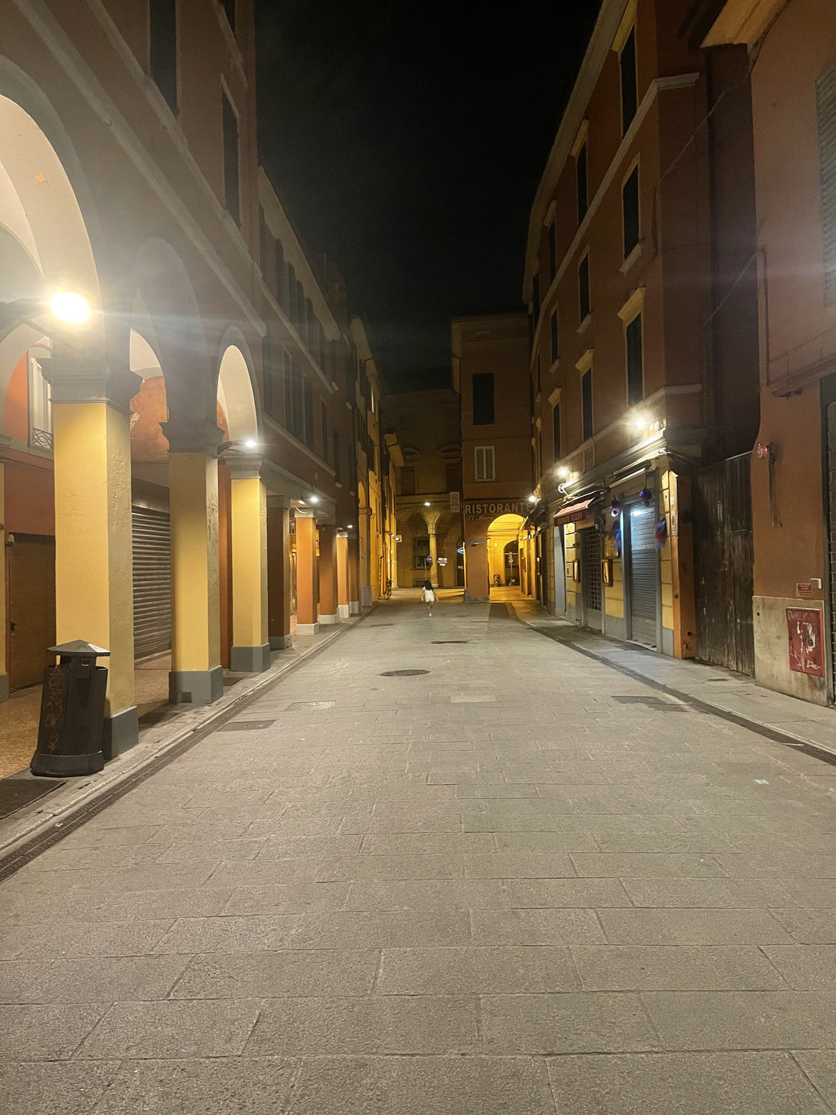 A quiet porticoed street in Bologna at night