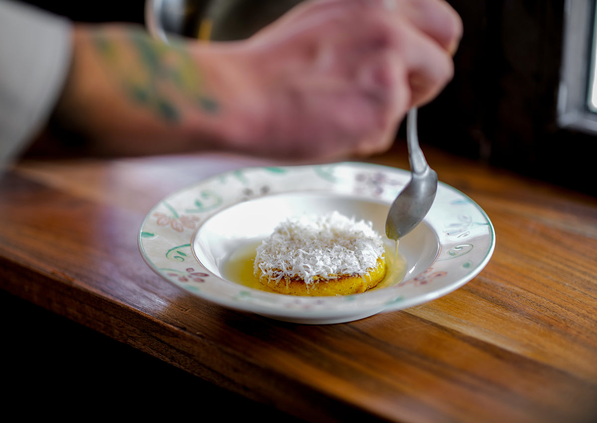 A dish topped with grated cheese being finished with a spoon at Ahimè