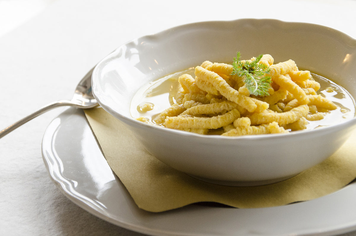 A bowl of passatelli in clear broth at Osteria Bartolini