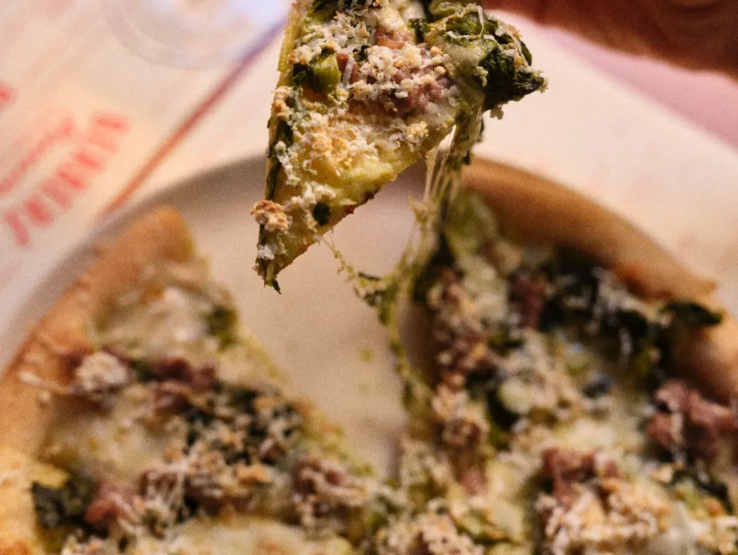 A slice of pizza with sausage and friarielli lifted from the pie at Berberè
