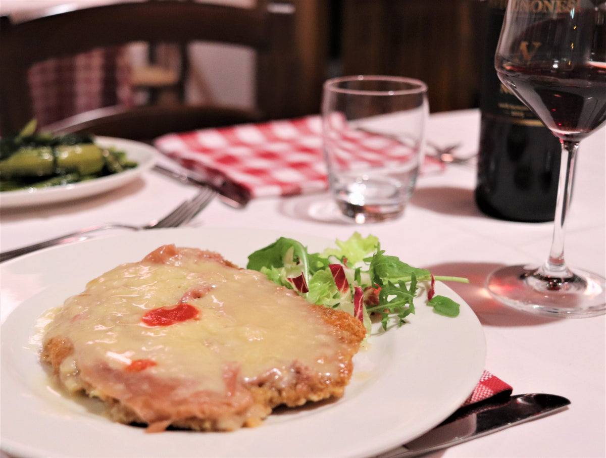 A cotoletta alla bolognese with salad and a glass of red wine at Dal Biassanot
