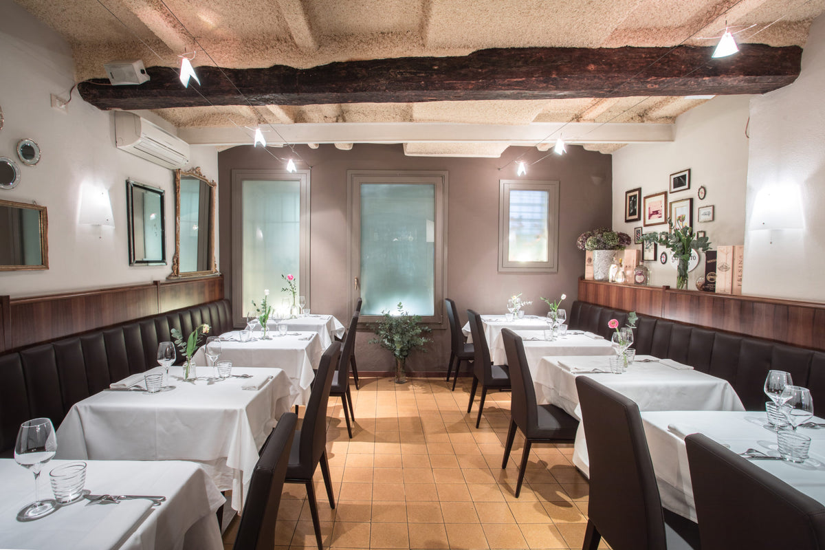 The dining room with white tablecloths and a beamed ceiling at Caminetto d'Oro