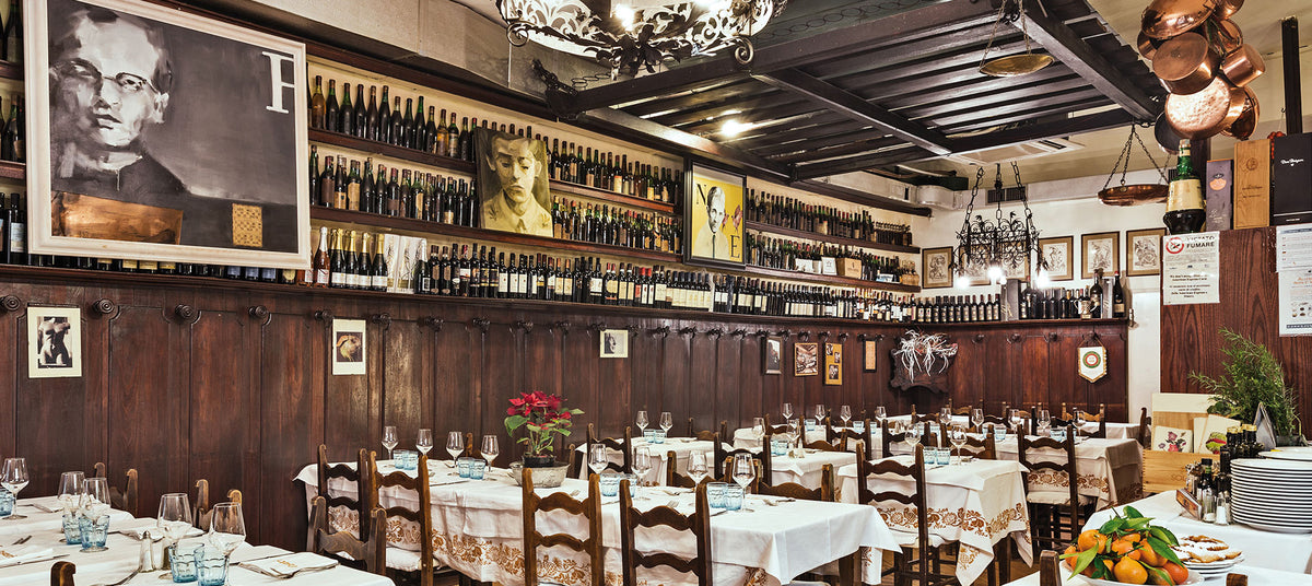 Tables set beneath walls lined with wine bottles at Da Cesari