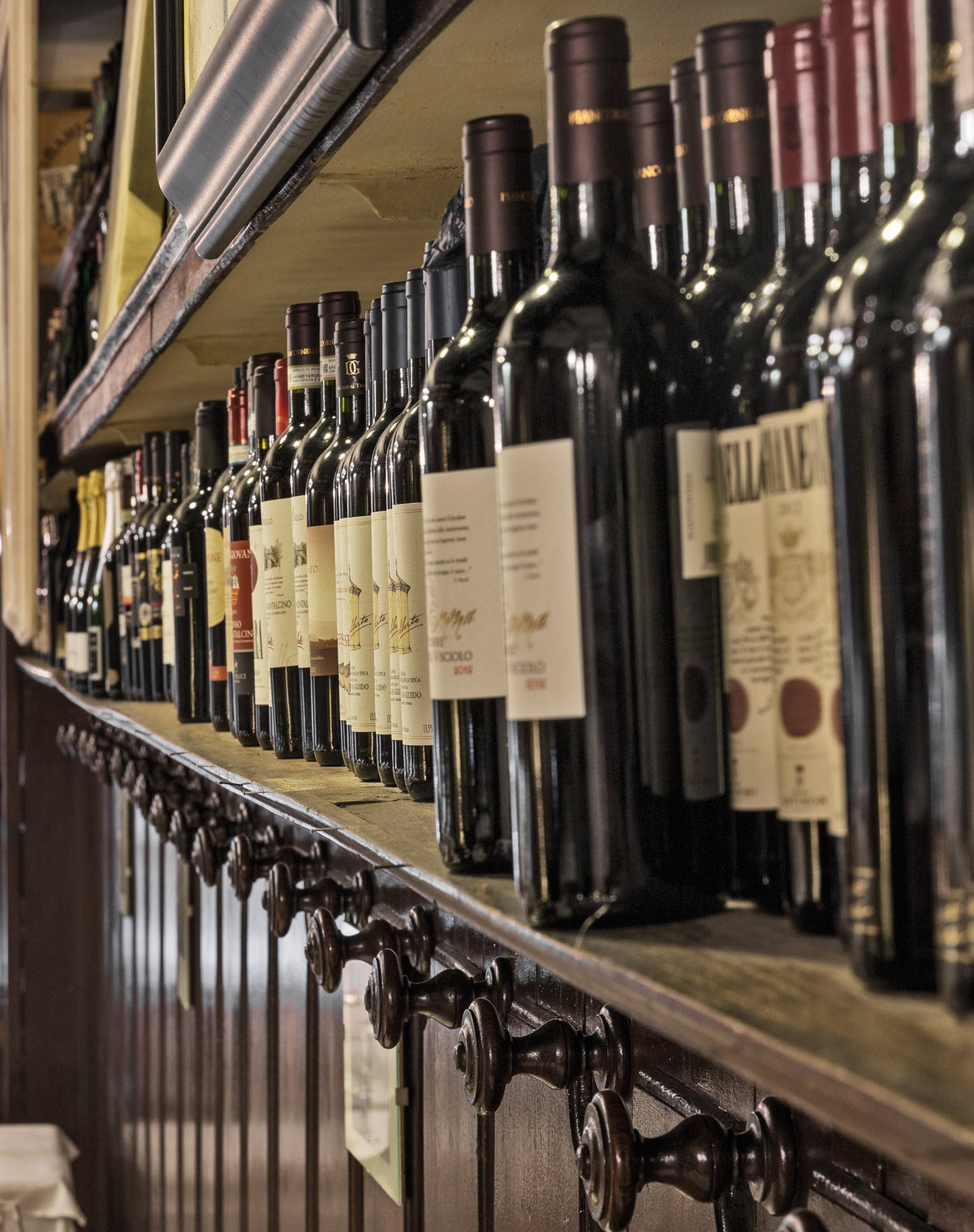 Bottles of red wine on wooden shelves at Da Cesari