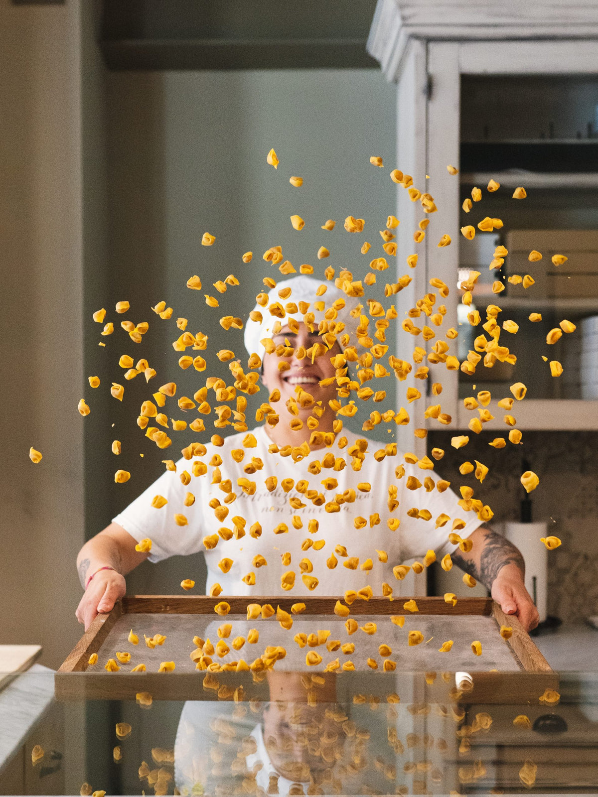 A pasta maker tossing fresh pasta from a tray at Da Me