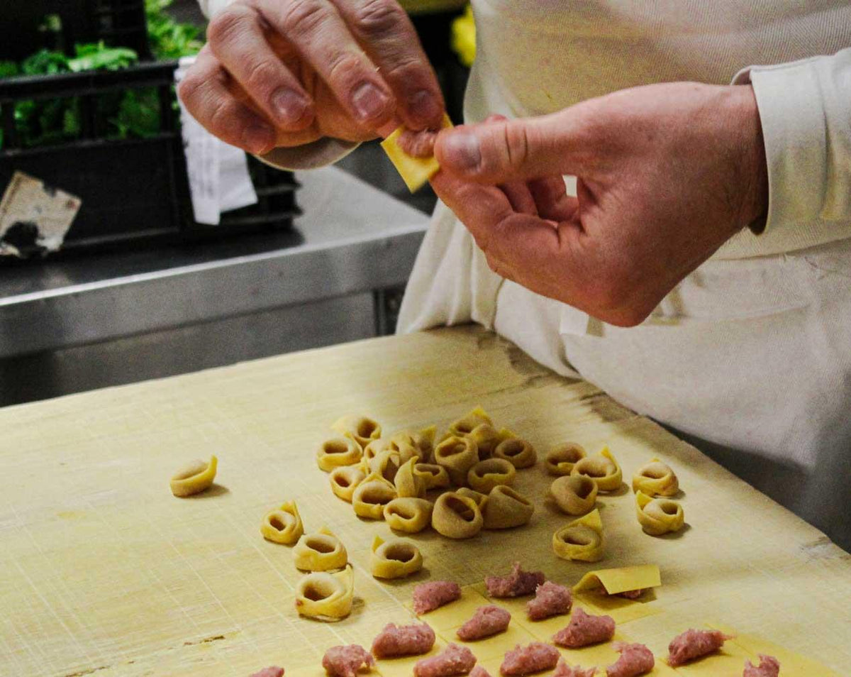 Hands folding fresh tortellini at Da Nello