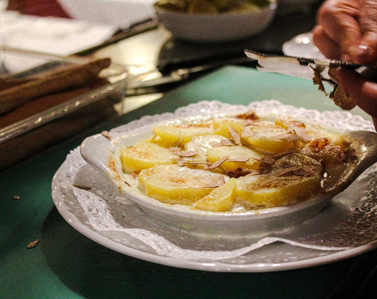 A dish of sliced potatoes being finished with shaved truffle at Da Nello