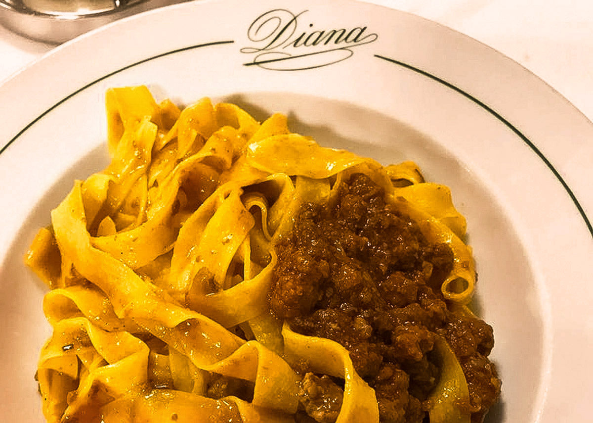 Tagliatelle with ragù on a monogrammed plate at Diana