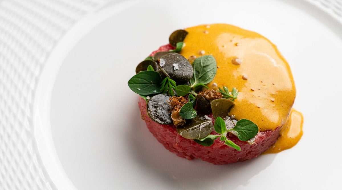A tartare topped with herbs and a yellow sauce at I Carracci