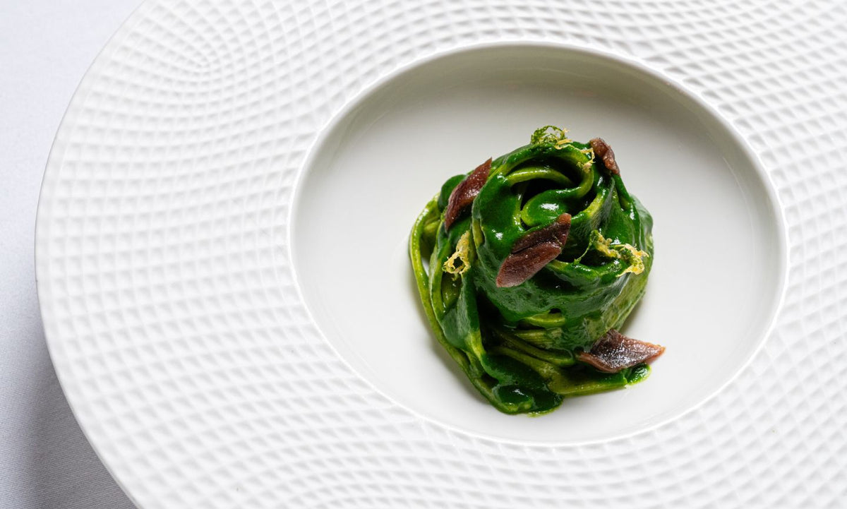 A nest of green pasta in a white bowl at I Carracci