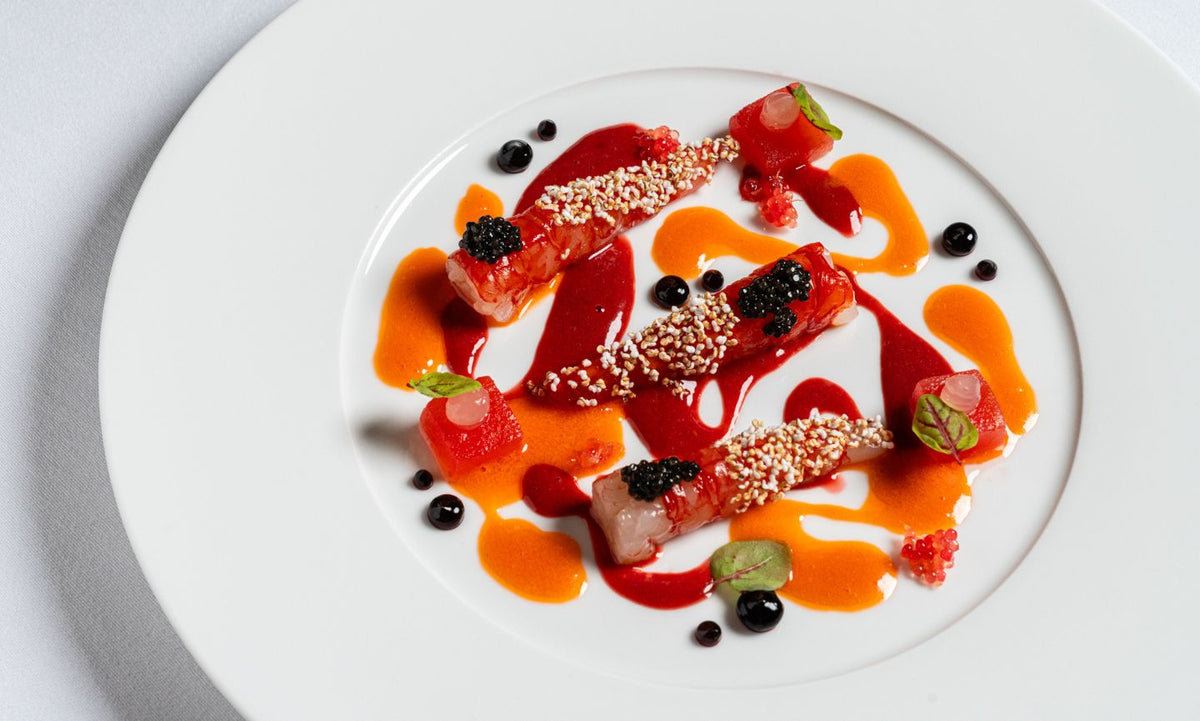 Sliced raw fish with red and orange sauces at I Carracci