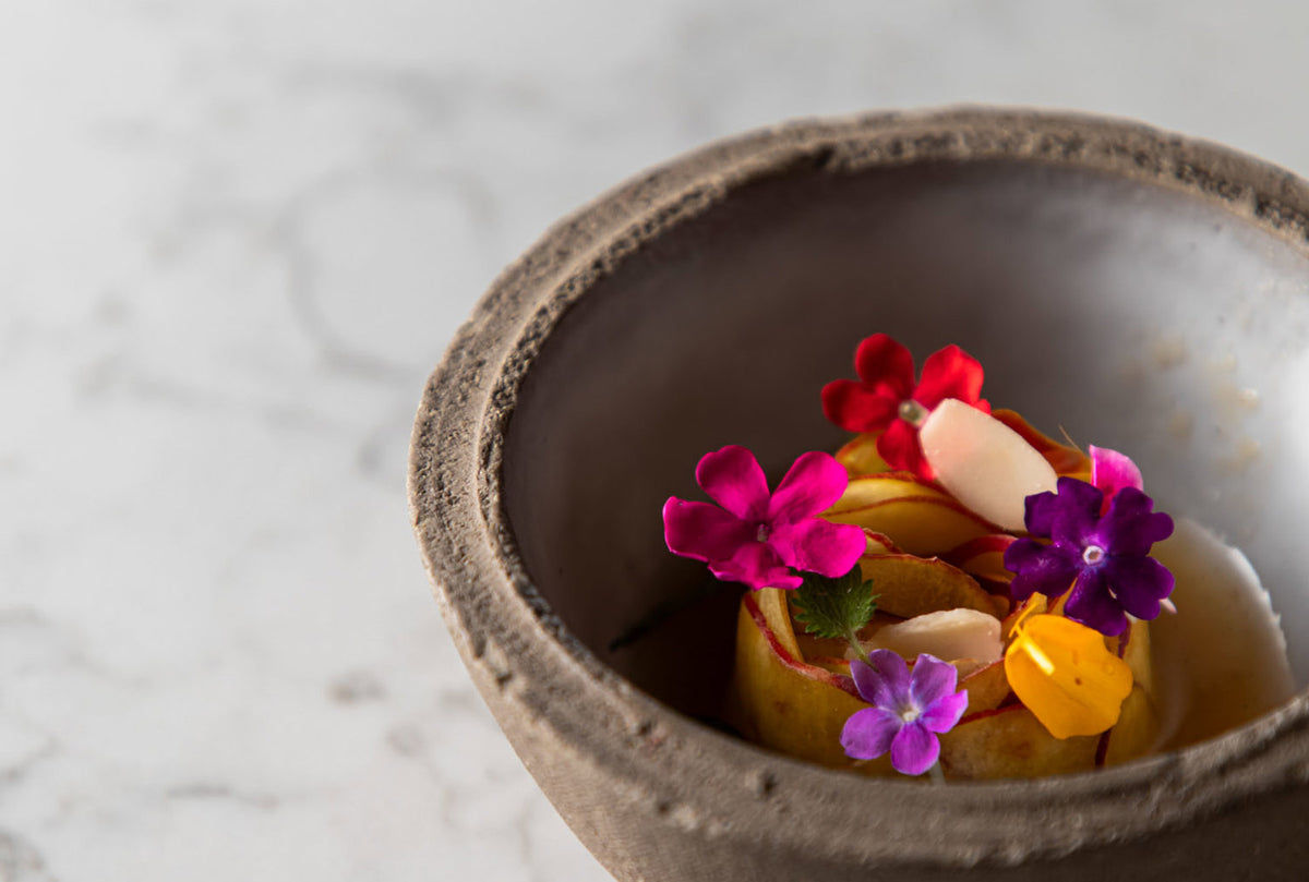A dish garnished with edible flowers in a stone bowl at I Portici