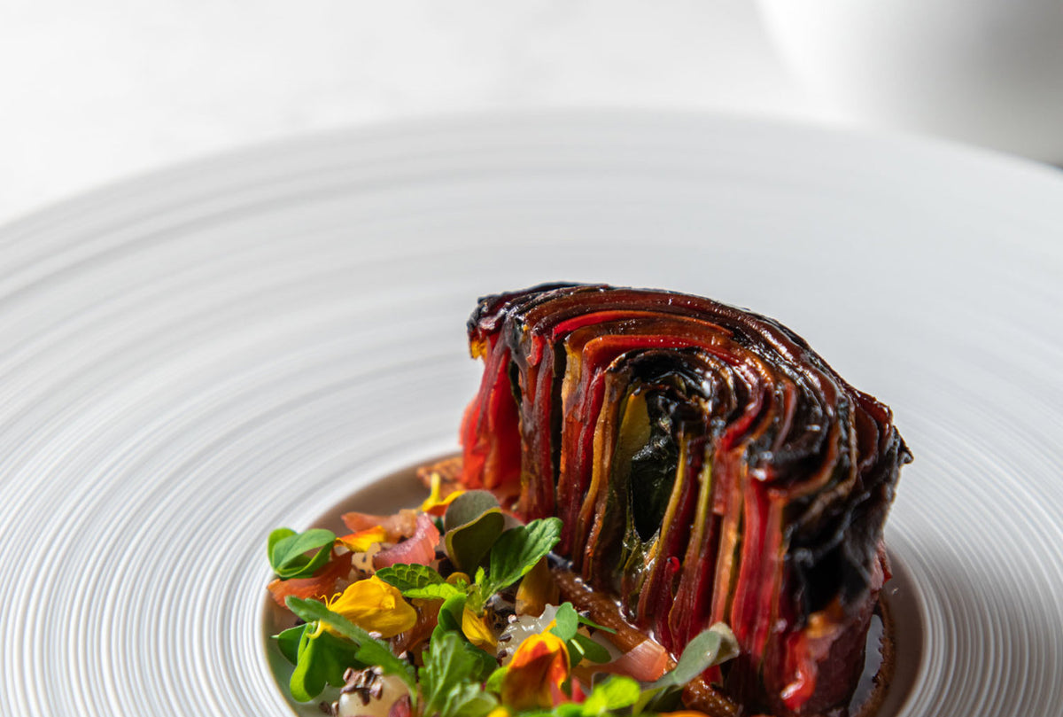 A layered vegetable dish with a charred top and herbs at I Portici