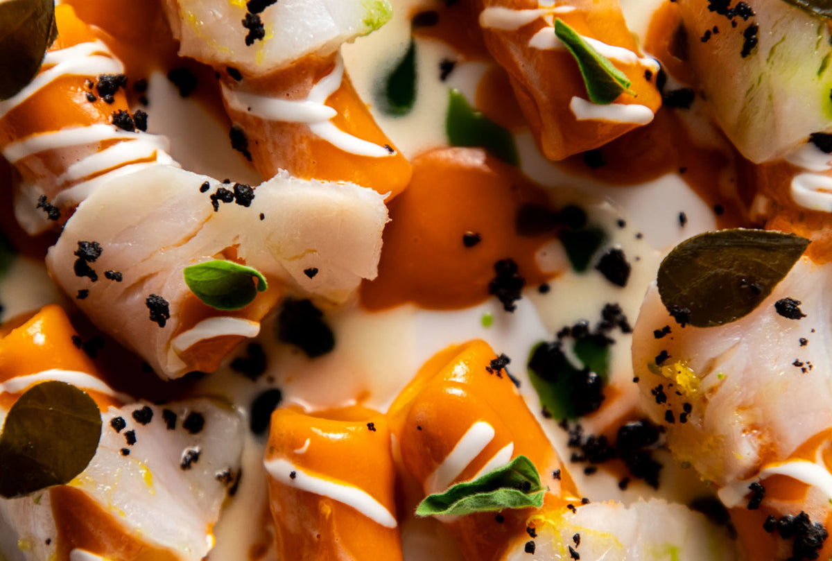Close-up of white fish with orange sauce and herbs at I Portici