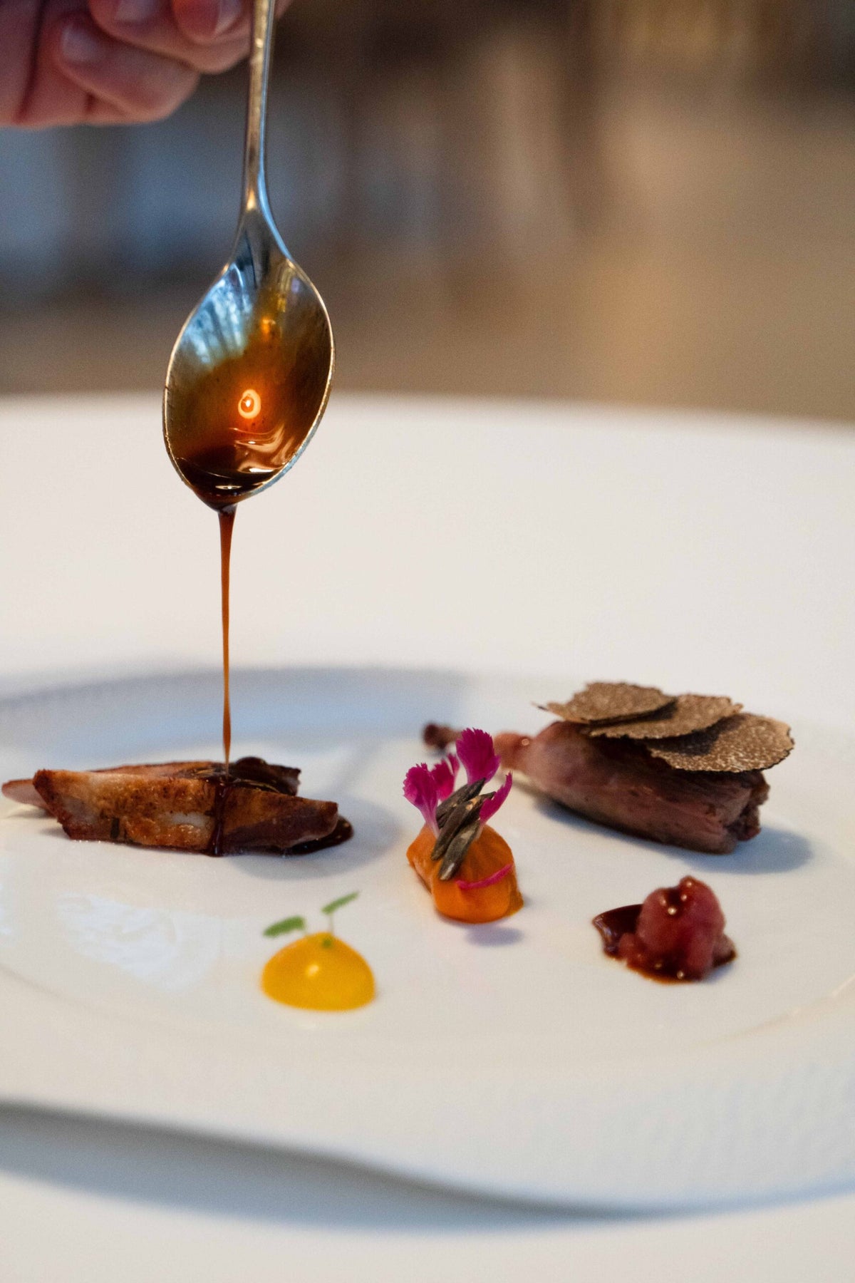 Sauce being spooned over a plated tasting course at La Porta