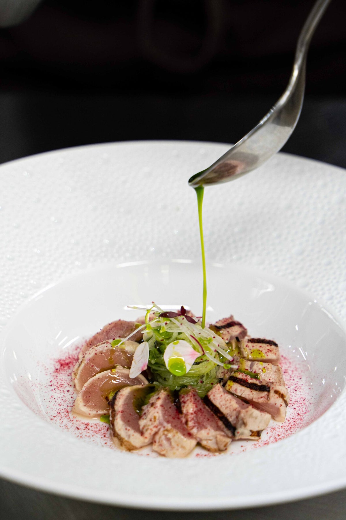 Green oil drizzled over seared slices with microgreens at La Porta