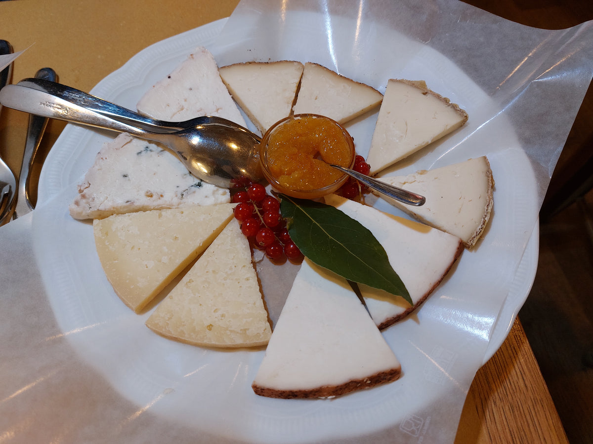A platter of assorted cheeses with a small jar of preserve at Osteria Bottega