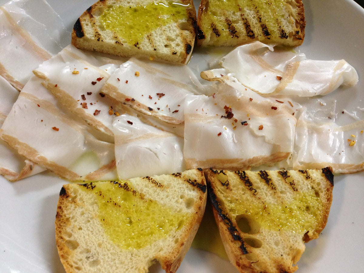 Thin slices of cured lard with grilled bread at Posta