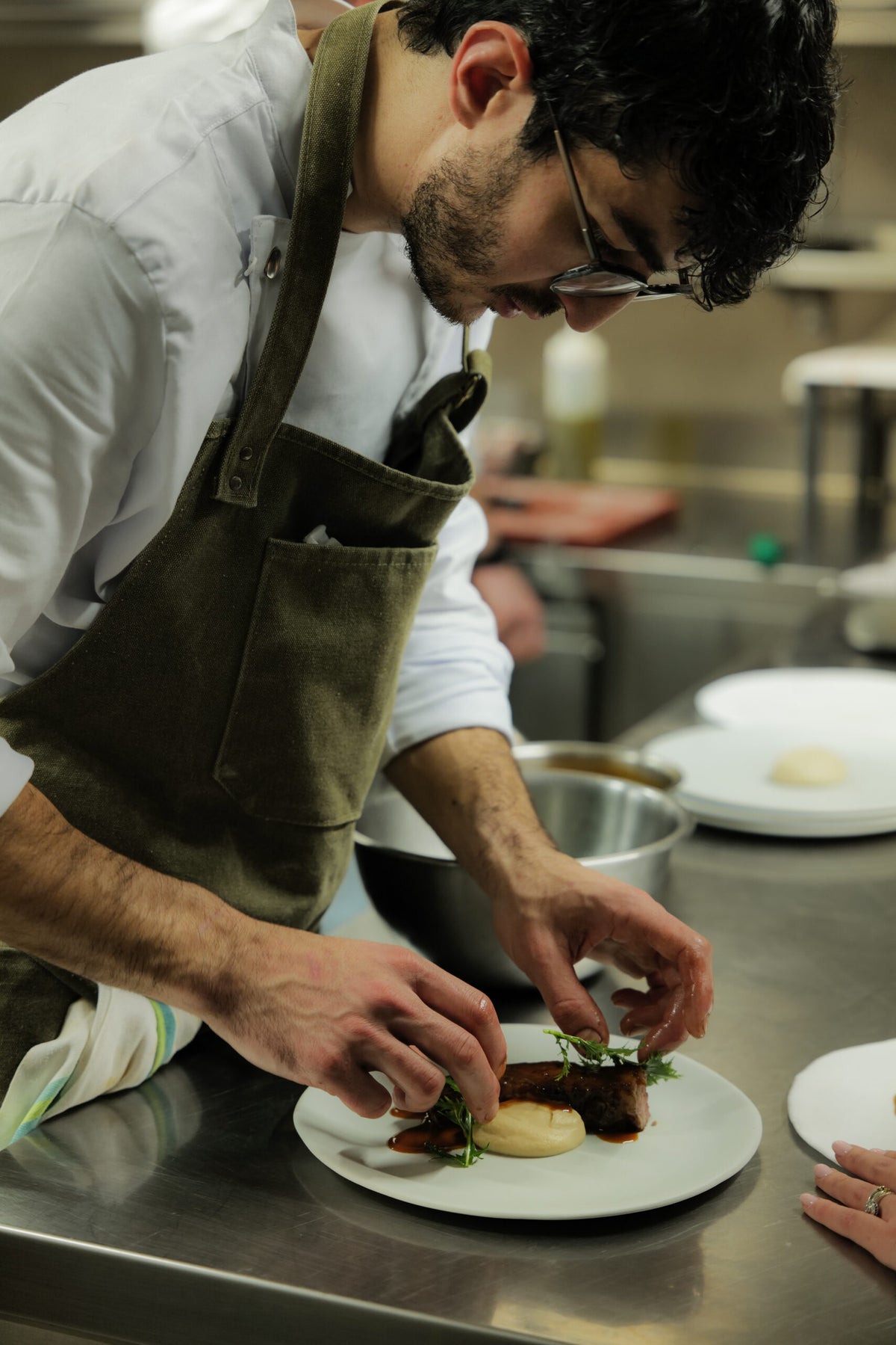 The chef plating a dish in the kitchen at Scacco Matto
