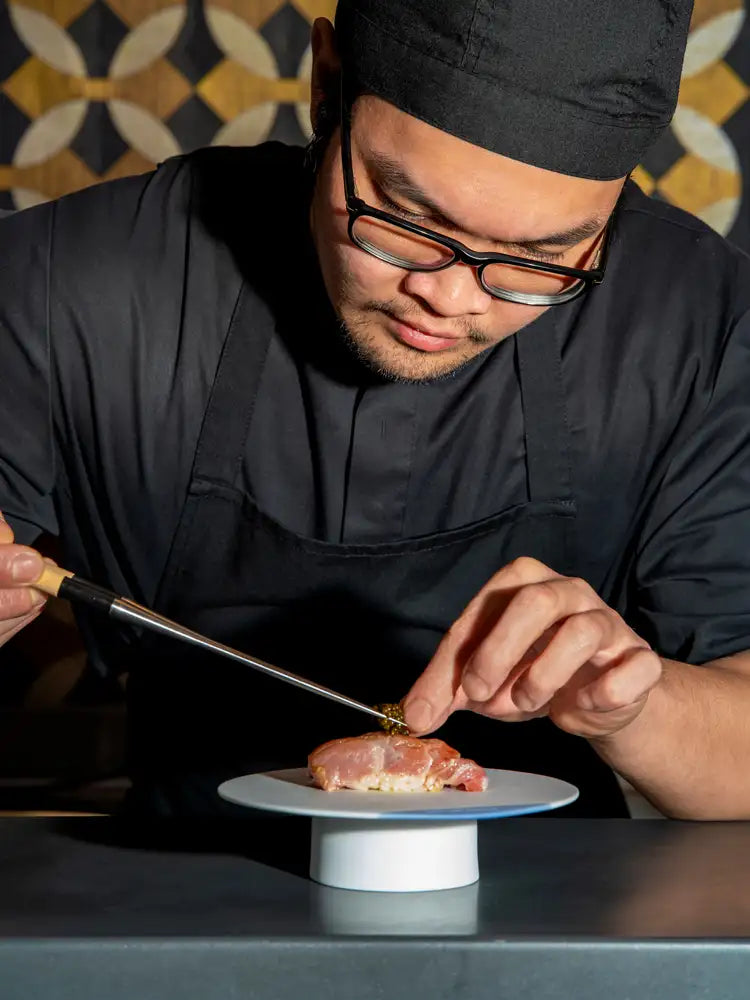 A chef plating nigiri with tweezers at Seta