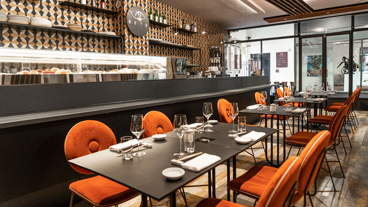 The dining room with orange chairs beside the sushi counter at Seta