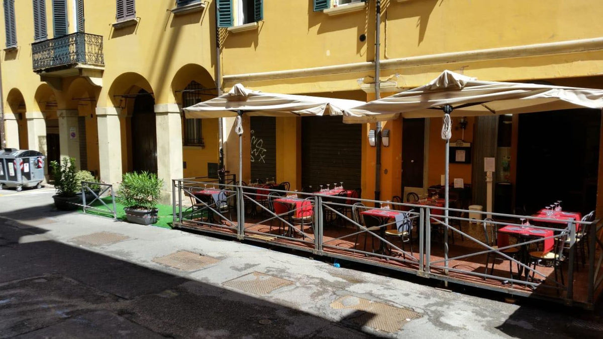 Outdoor tables under umbrellas at Trattoria Trebbi