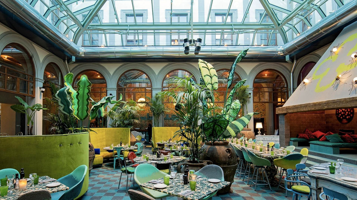 Glass-roofed courtyard restaurant with tropical plants at 25hours Hotel Florence Piazza San Paolino