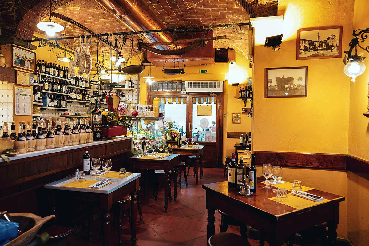 Dining room with wooden tables and wine shelves at Antico Ristoro di Cambi