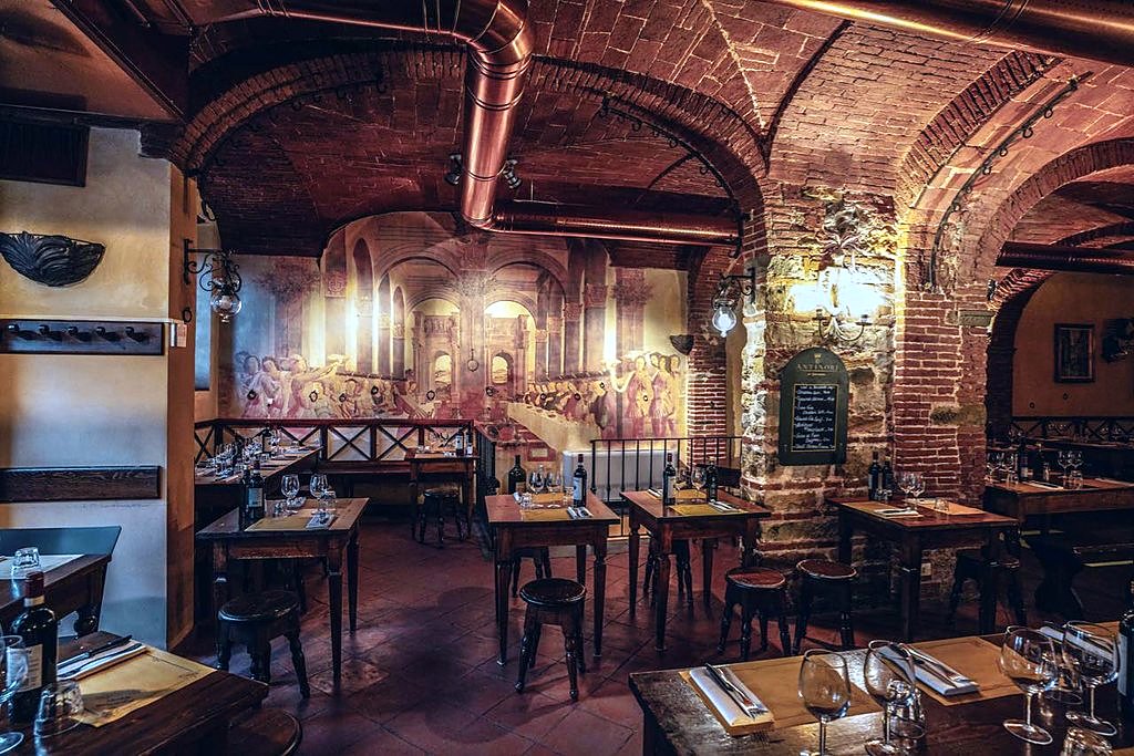 Vaulted brick dining room with a frescoed wall at Antico Ristoro di Cambi