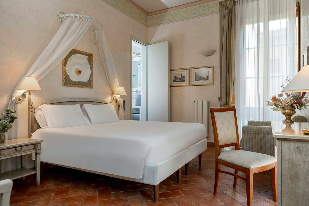 Superior double room with canopy drape and terracotta floor at Hotel Davanzati