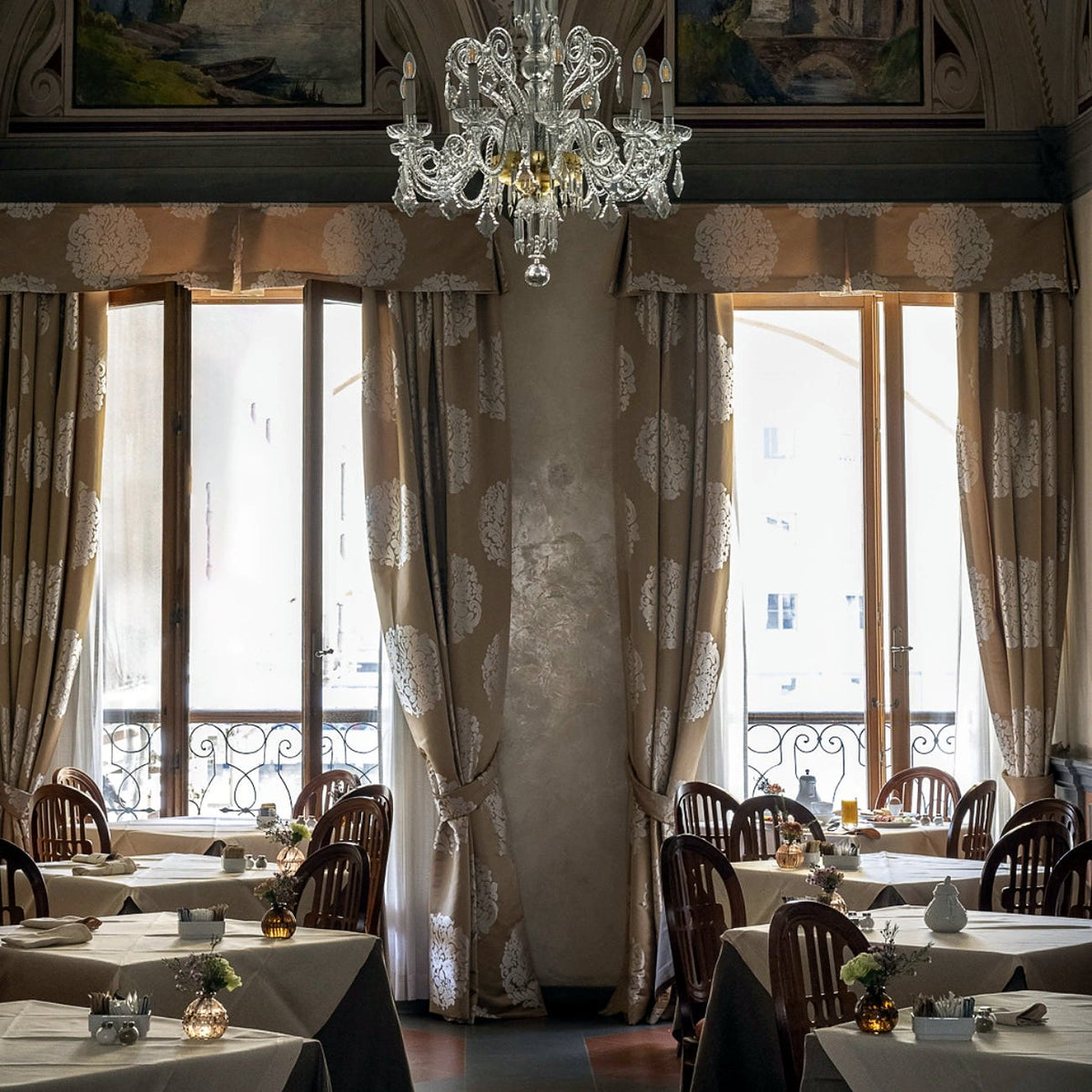 Breakfast room with crystal chandelier and tall windows at Hotel degli Orafi