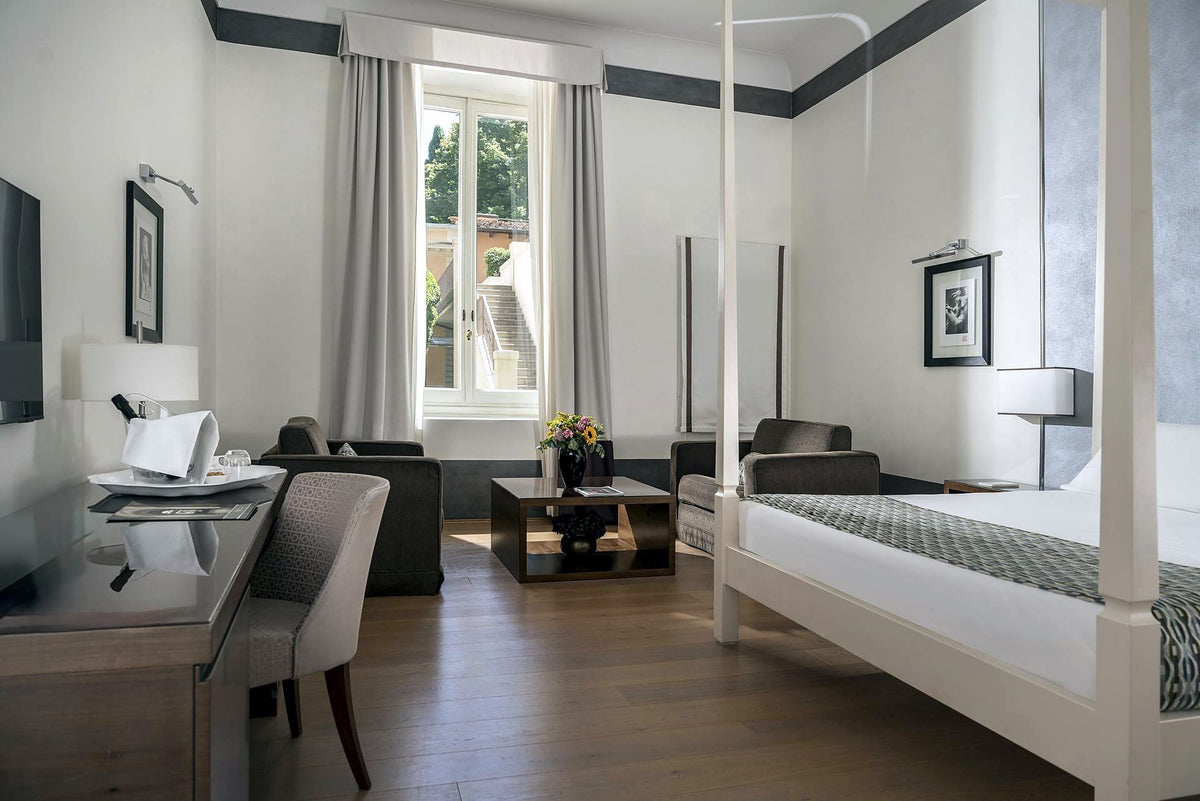 Junior suite with four-poster bed and sitting area at Hotel Orto de' Medici