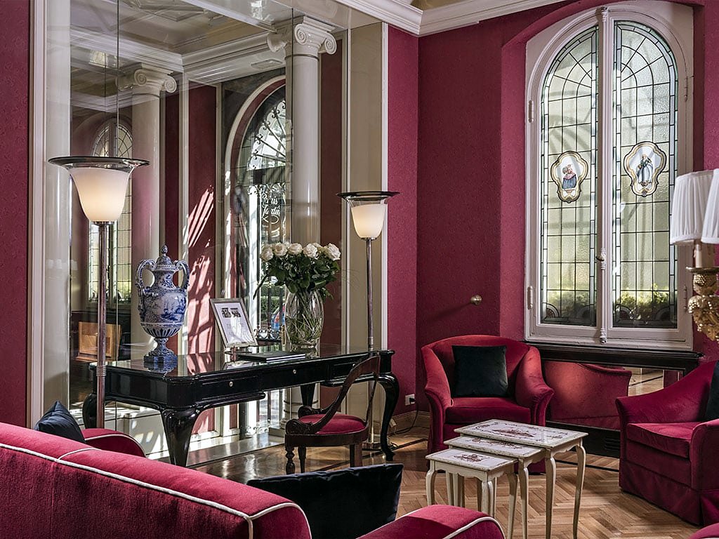 Red salon with stained-glass window and velvet armchairs at Hotel Regency