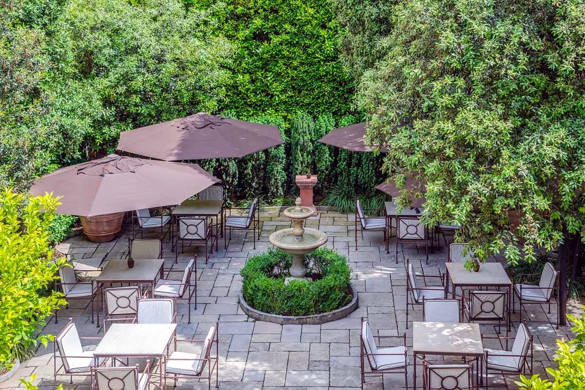 Garden courtyard with fountain, tables and parasols at Hotel Regency