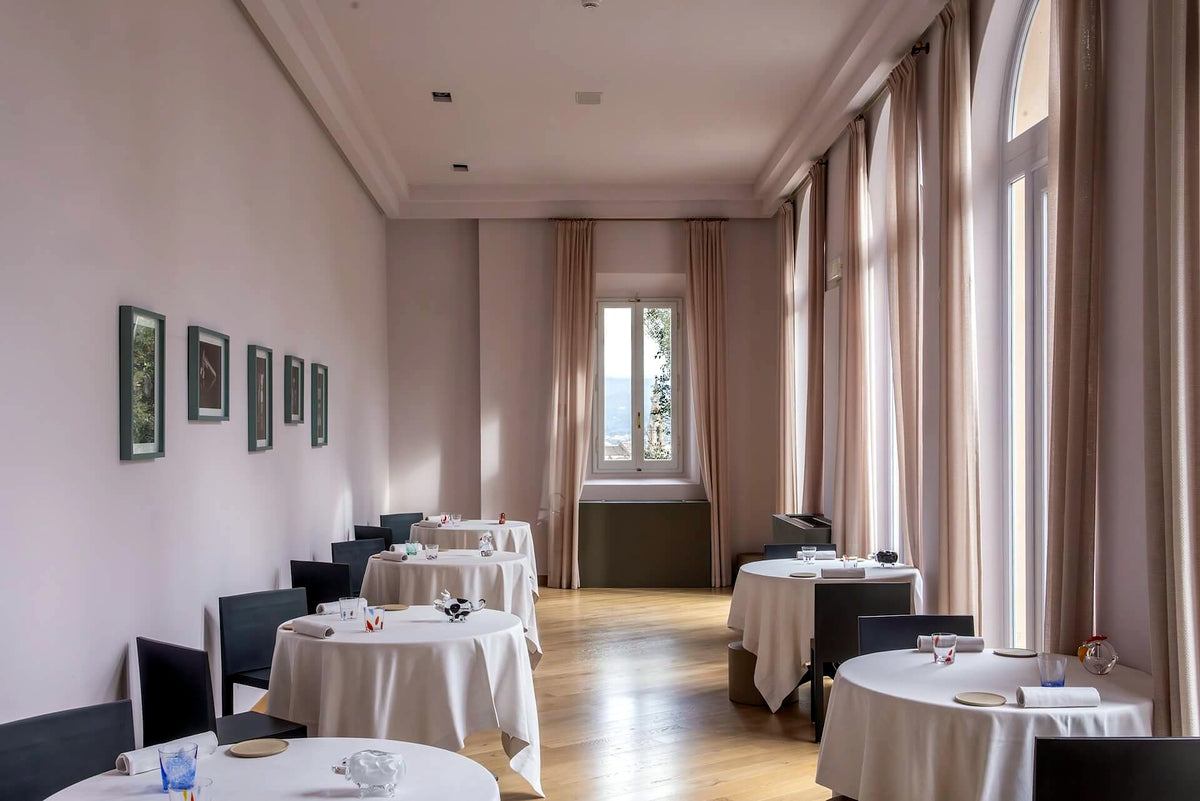 Long dining room with round tables at La Leggenda dei Frati