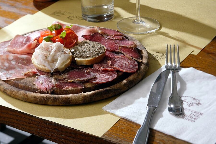 Tuscan cured meats and crostini on a wooden board at Osteria del Cinghiale Bianco
