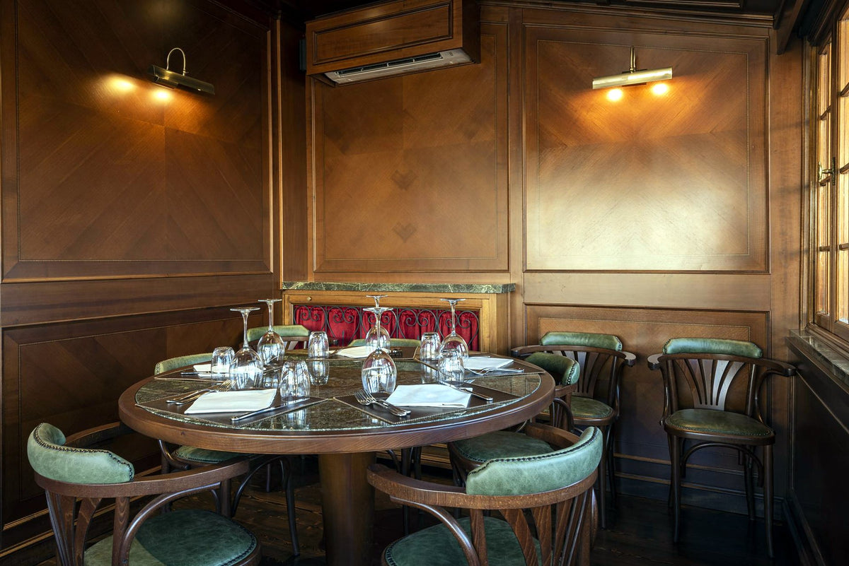 Wood-panelled dining room with a round table at Osteria delle Tre Panche