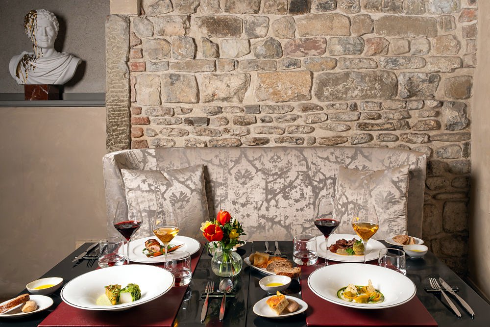 Table set with dishes against a stone wall at Osteria Pagliazza
