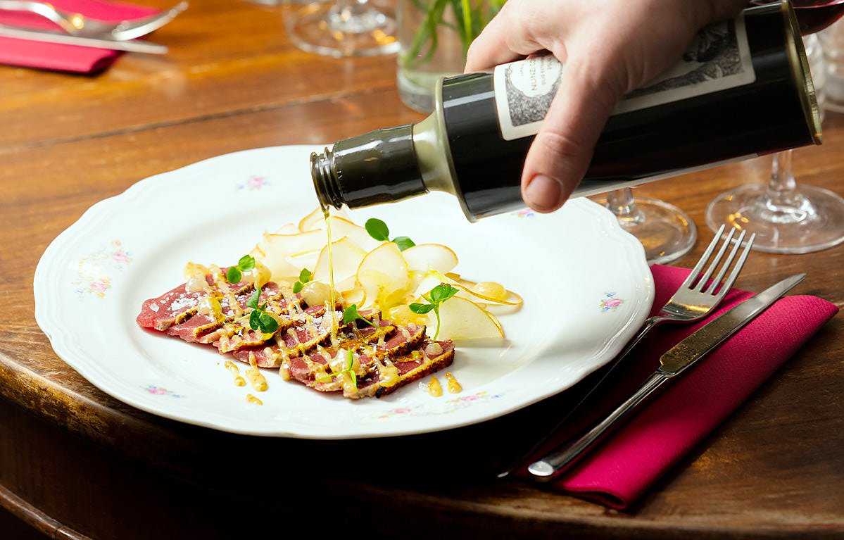 Olive oil poured over carpaccio at Osteria Pastella