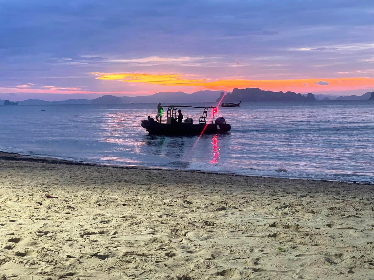 A boat crew coming ashore at dusk, island silhouettes over the Andaman Sea