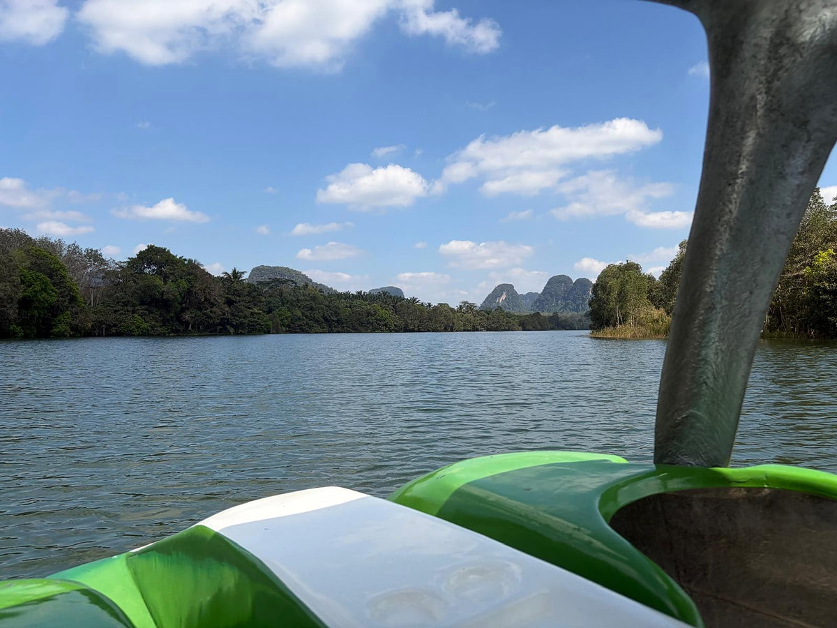 Limestone hills beyond a quiet lake, seen from a pedal boat in the Krabi countryside