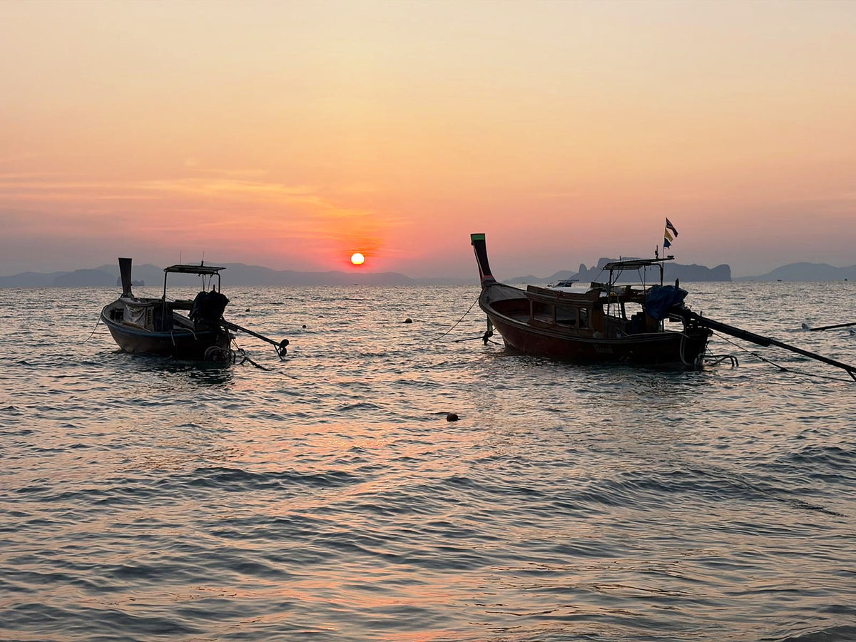 Longtail boats at anchor as the sun sets over the Andaman Sea near Ao Nang